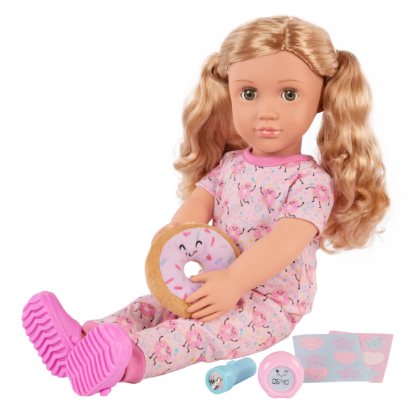 Doll dressed in pajamas holding plush donut and other accessories