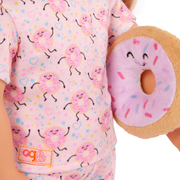 Our Generation Doll wearing pajama tops with donut motif on fabric, holding plush donut pillow