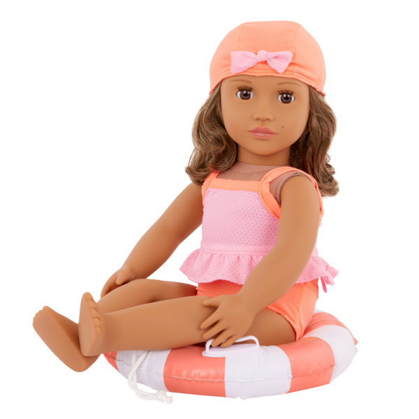 Our Generation Doll wearing the Deluxe Outfit "Floaty Fun" sitting on a donut shaped floatie and wearing a bathing cap