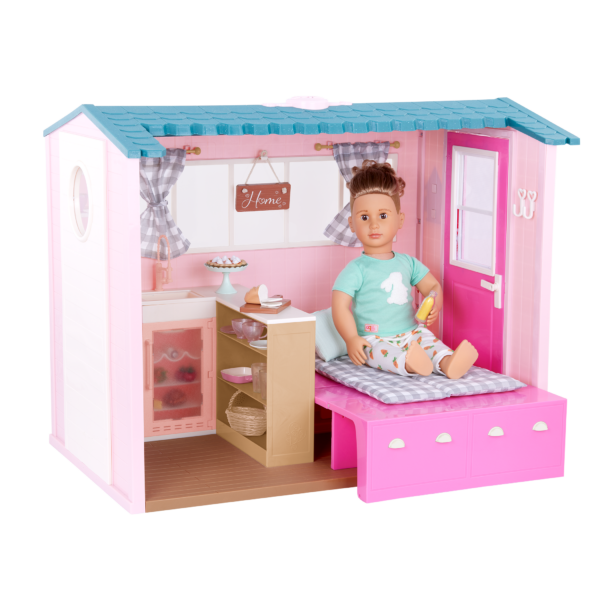 An Our Generation 18-inch Doll sitting in the Country House set up as a bedroom