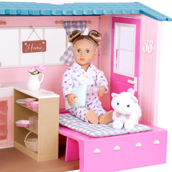 An Our Generation 18-inch Doll and her pet kitten sitting on the bed in the Country House